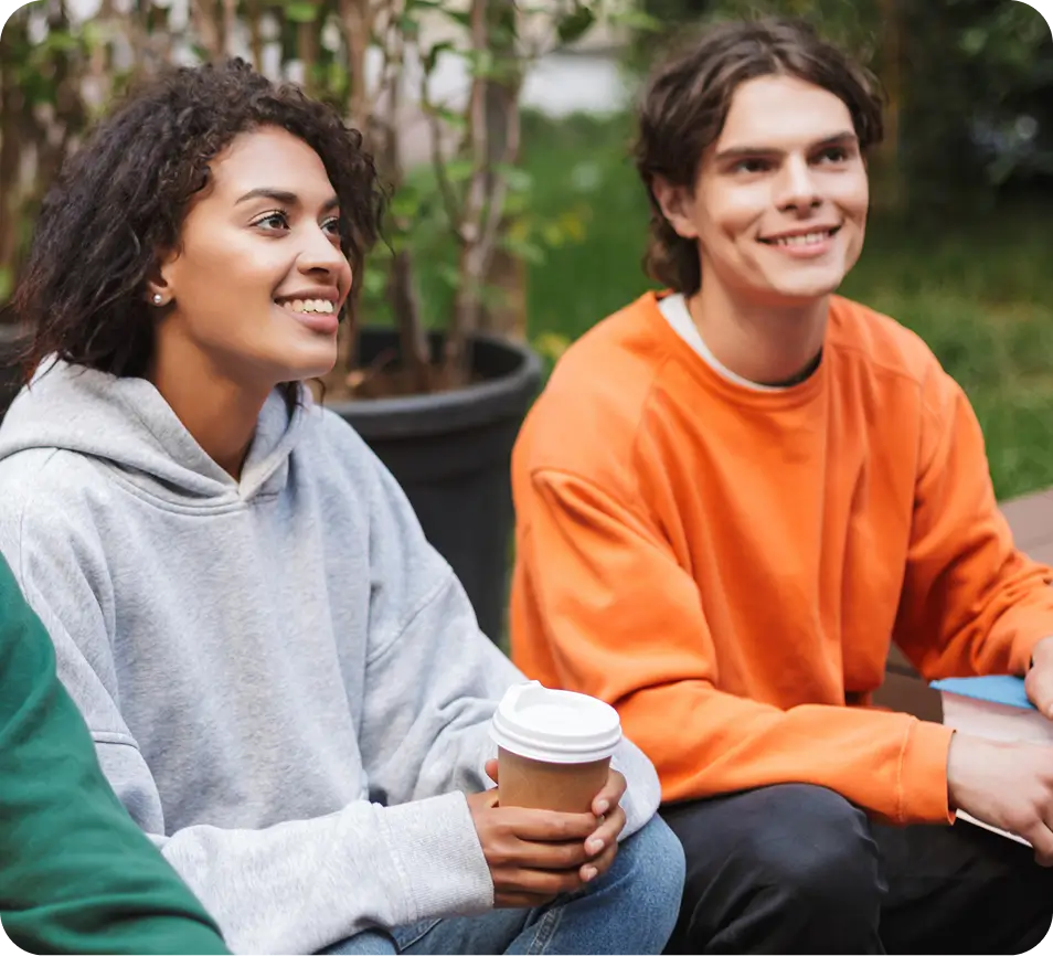 there are three people sitting on a bench with coffee cups