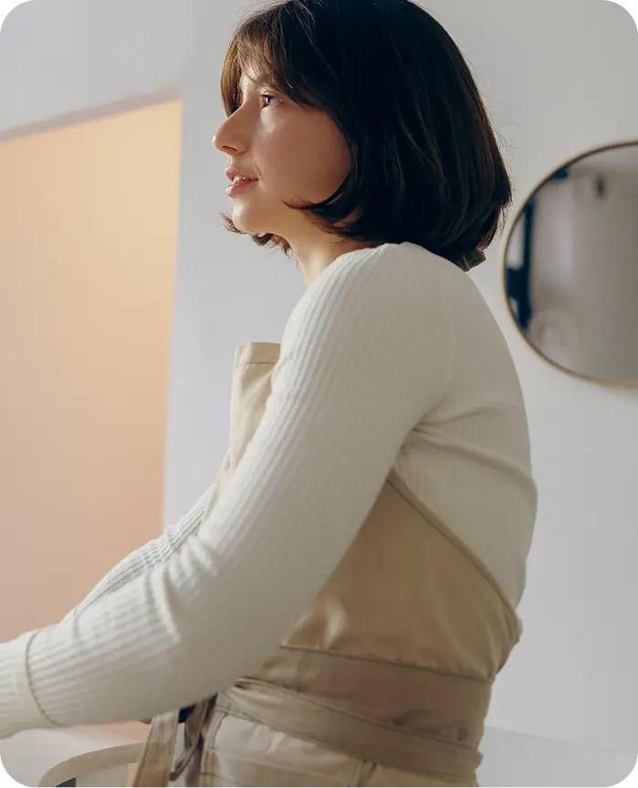 woman in white sweater and tan skirt holding a glass of wine