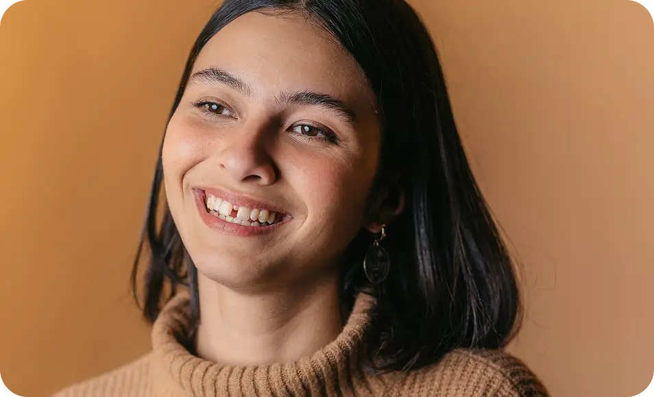 smiling woman with long black hair wearing a tan sweater