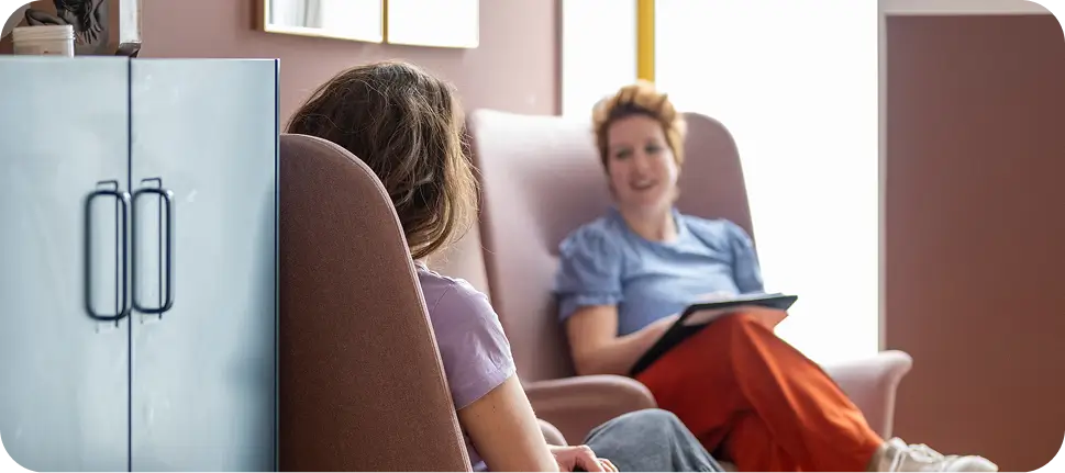 there are two women sitting in a chair with a tablet