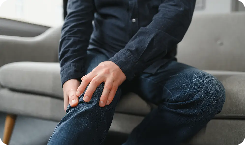 someone is sitting on a couch with their hands on their knees