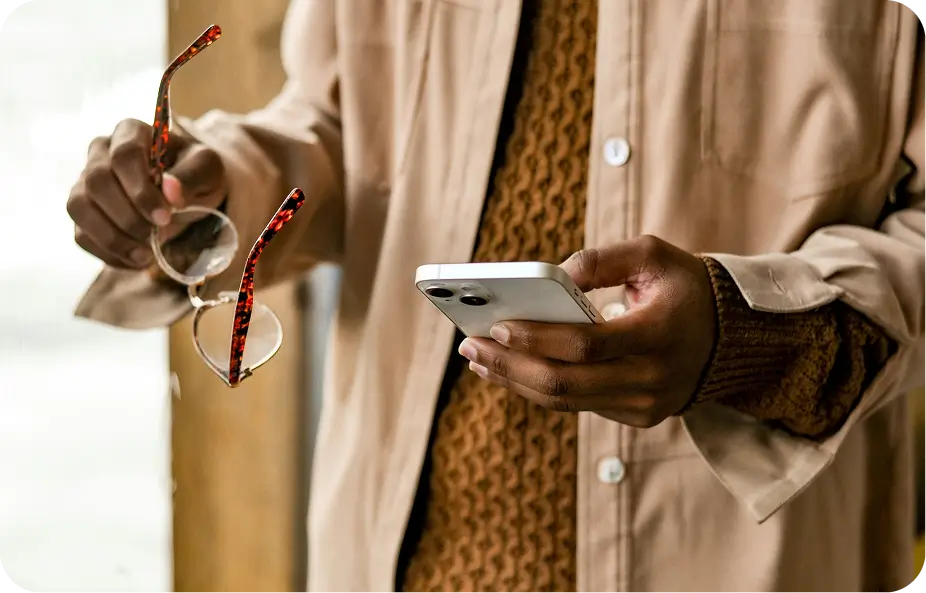 someone is holding a cell phone and wearing glasses