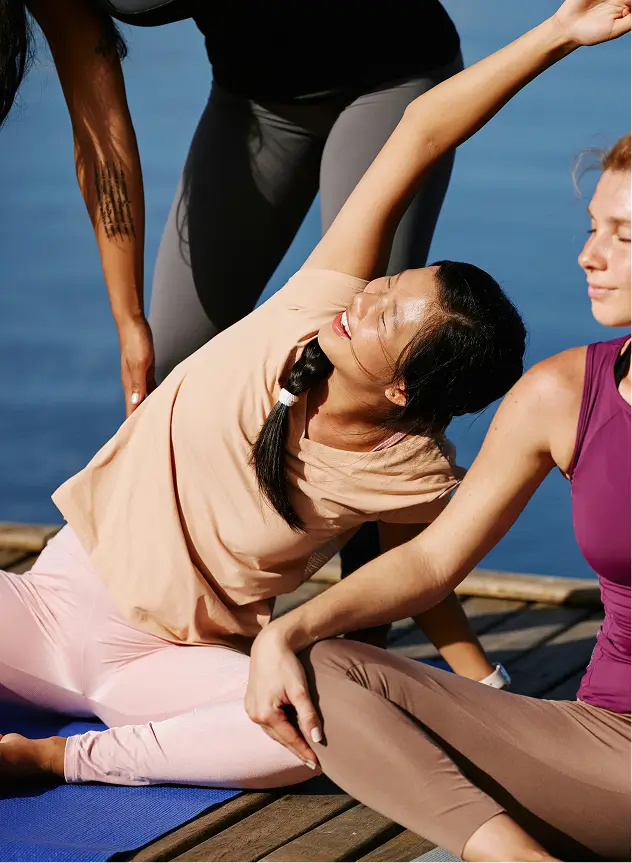 there are two women doing yoga on a dock by the water
