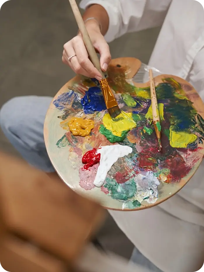 painting on a palette with a wooden brush