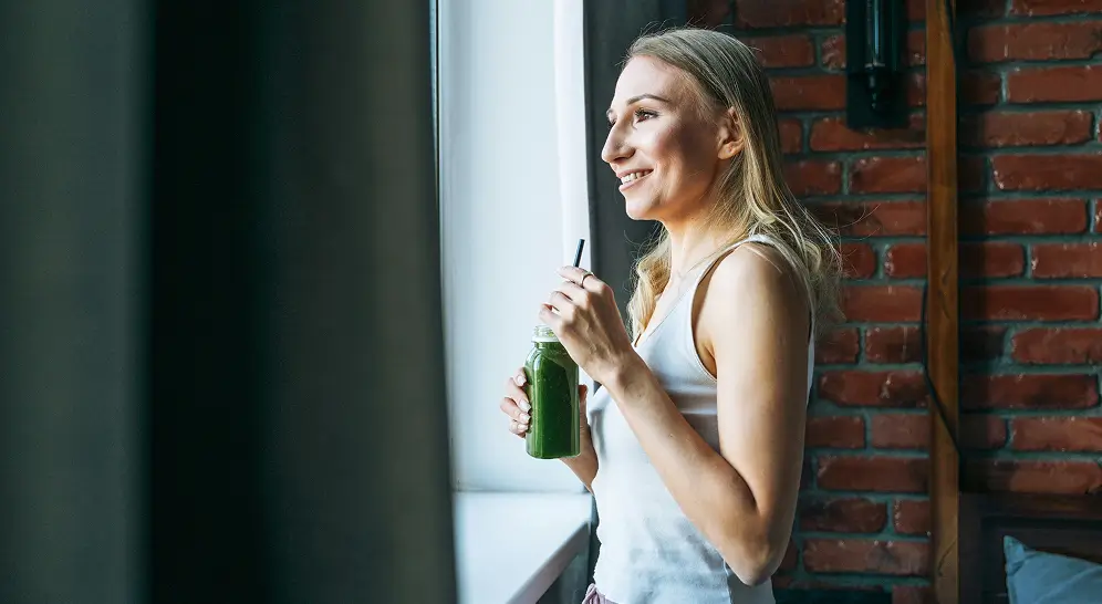 there is a woman holding a bottle of beer and looking out a window