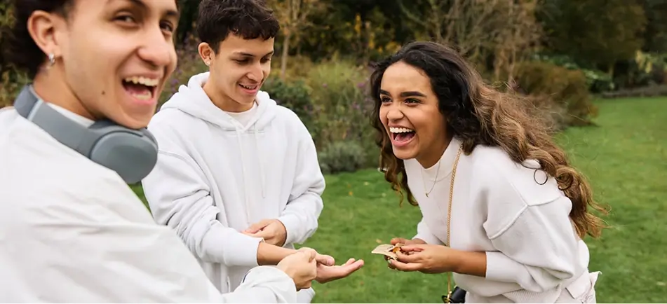 there are three people standing in a field laughing and eating