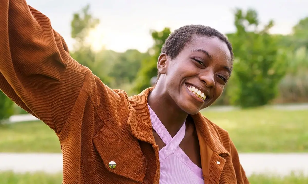 smiling woman in brown jacket holding up a cell phone