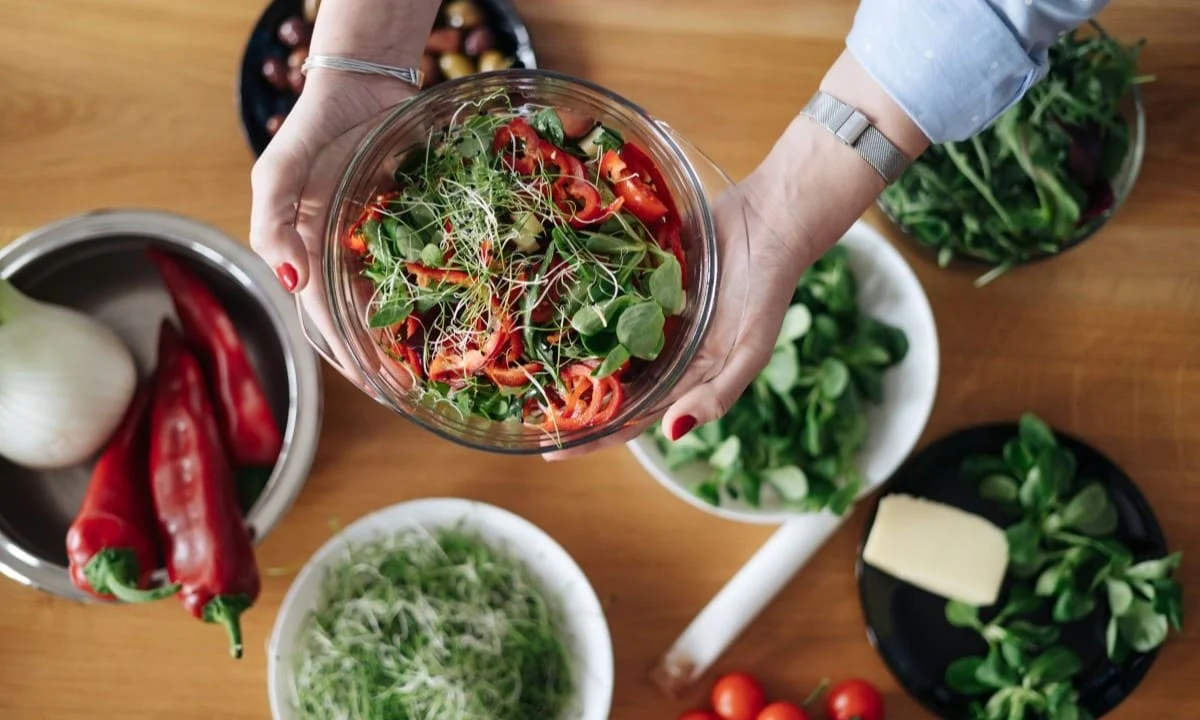 someone holding a bowl of vegetables and a bowl of other food