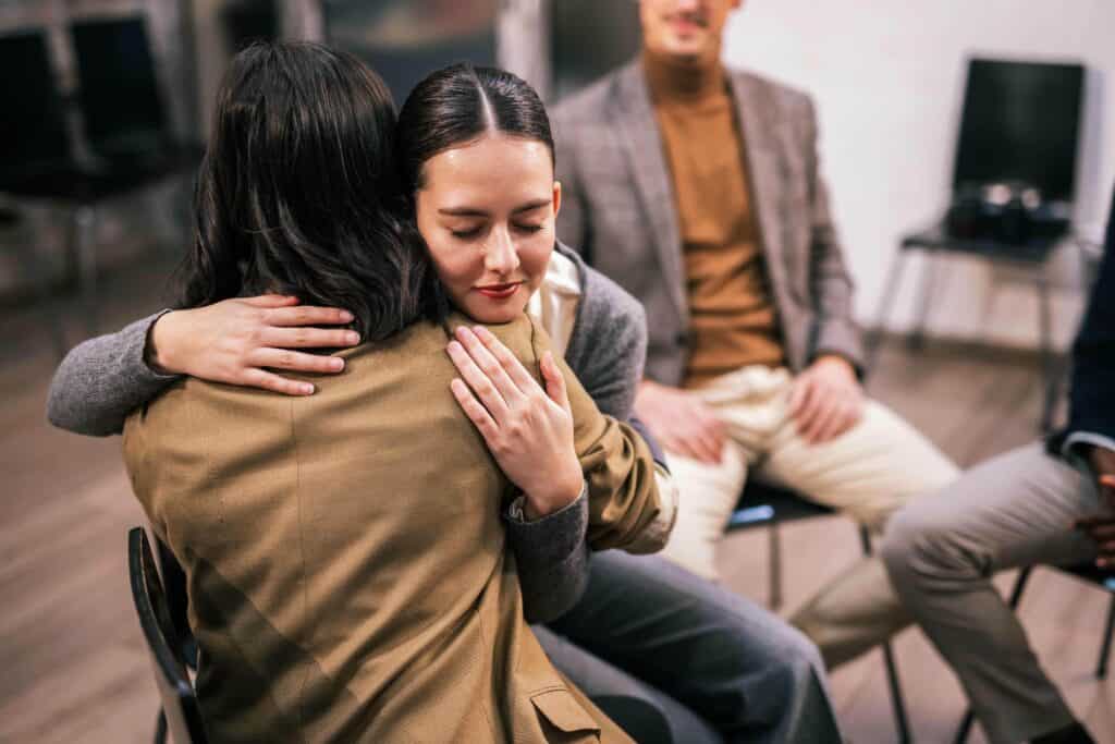 People embracing during a group therapy session as part of benzodiazepine addiction treatment in Massachusetts at Rebuilding Recovery Center.
