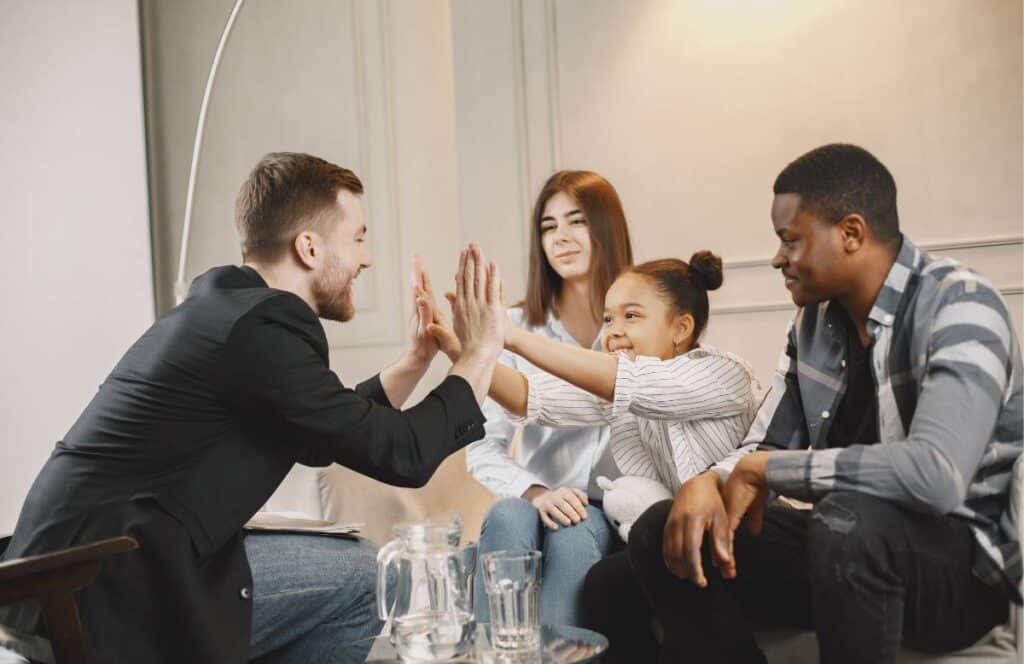 Therapist and child sharing a high five during family therapy in Massachusetts.