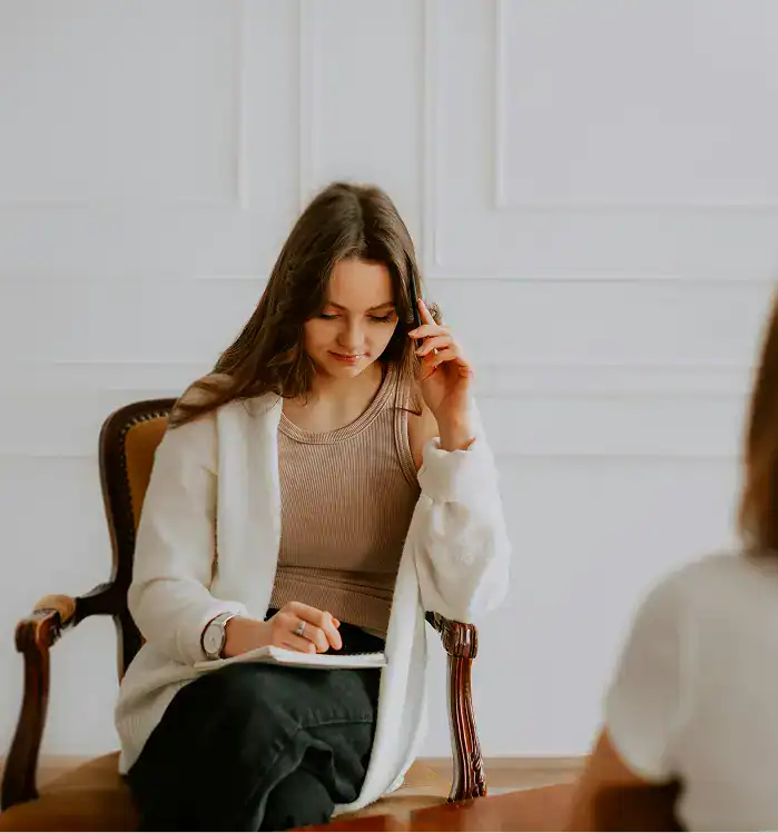 woman sitting in chair talking on cell phone while a doctor guiding for a Substance Abuse Treatment Programs in Massachusetts
