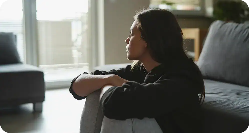 Woman sitting on a couch looking out the window.
