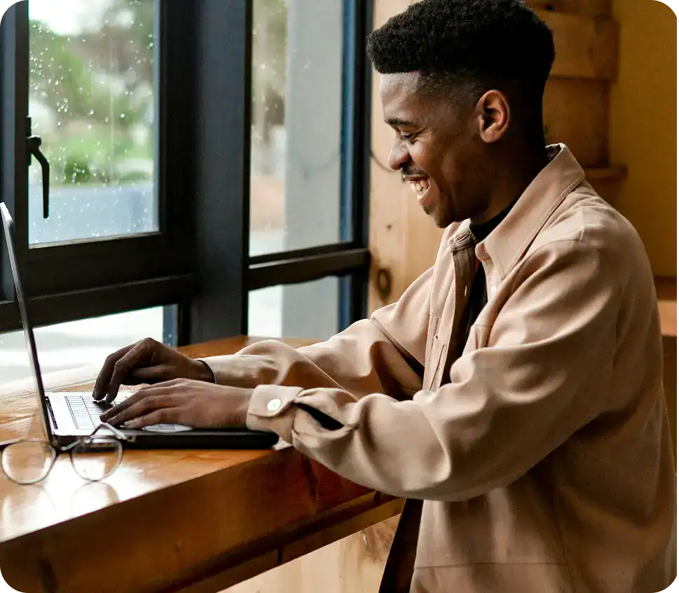 there is a man sitting at a table using a laptop waitng to do your Virtual Addiction Treatment in Massachusetts