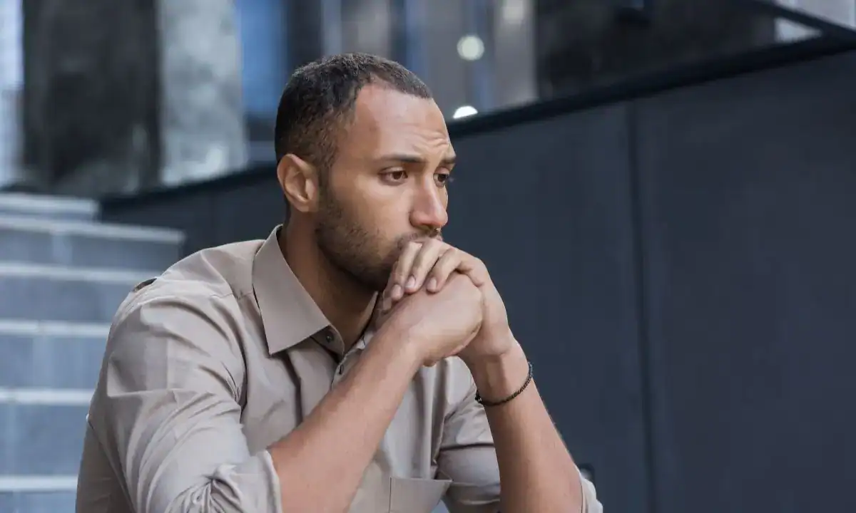arafed man sitting at a table with his hand on his chin