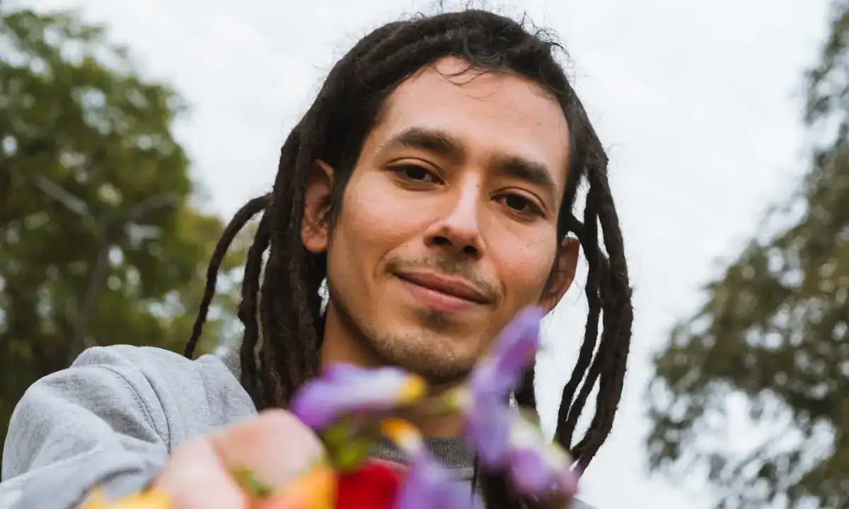 Person with dreadlocks holding flowers outside Rebuilding Recovery Center.