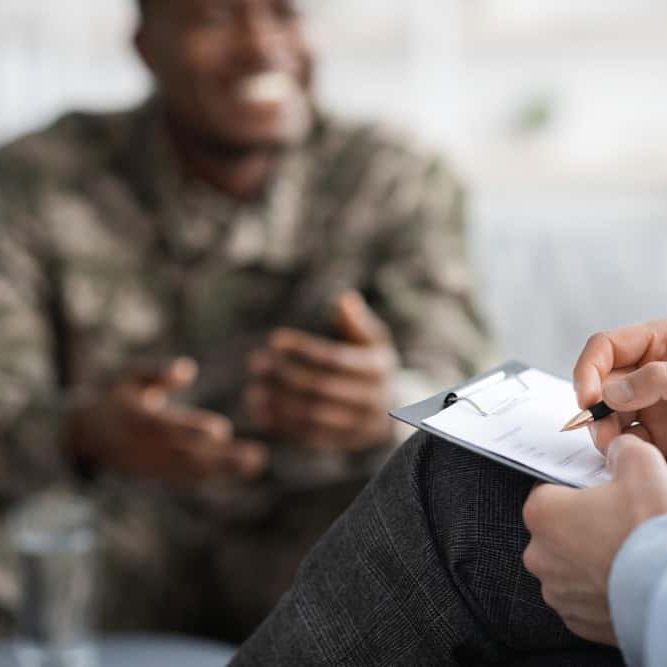 Black military service member speaking with a psychologist during addiction treatment for veterans in Easton, MA.
