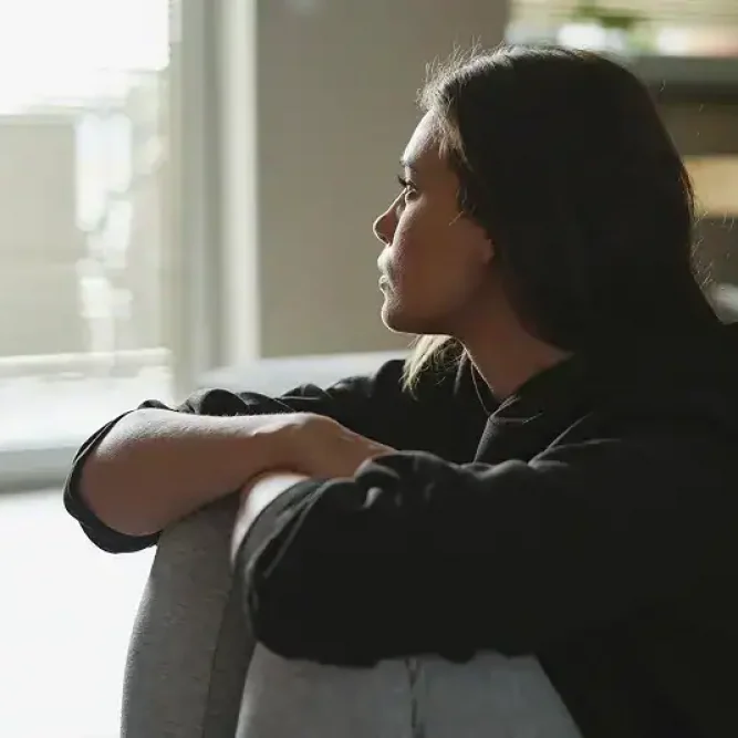 Woman sitting on a couch looking out the window.