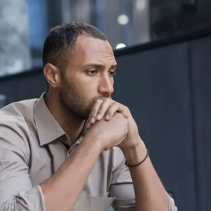 arafed man sitting at a table with his hand on his chin