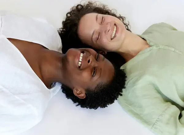 Two women lying on the floor, smiling and laughing, after participating in Substance Abuse Treatment Programs in Massachusetts